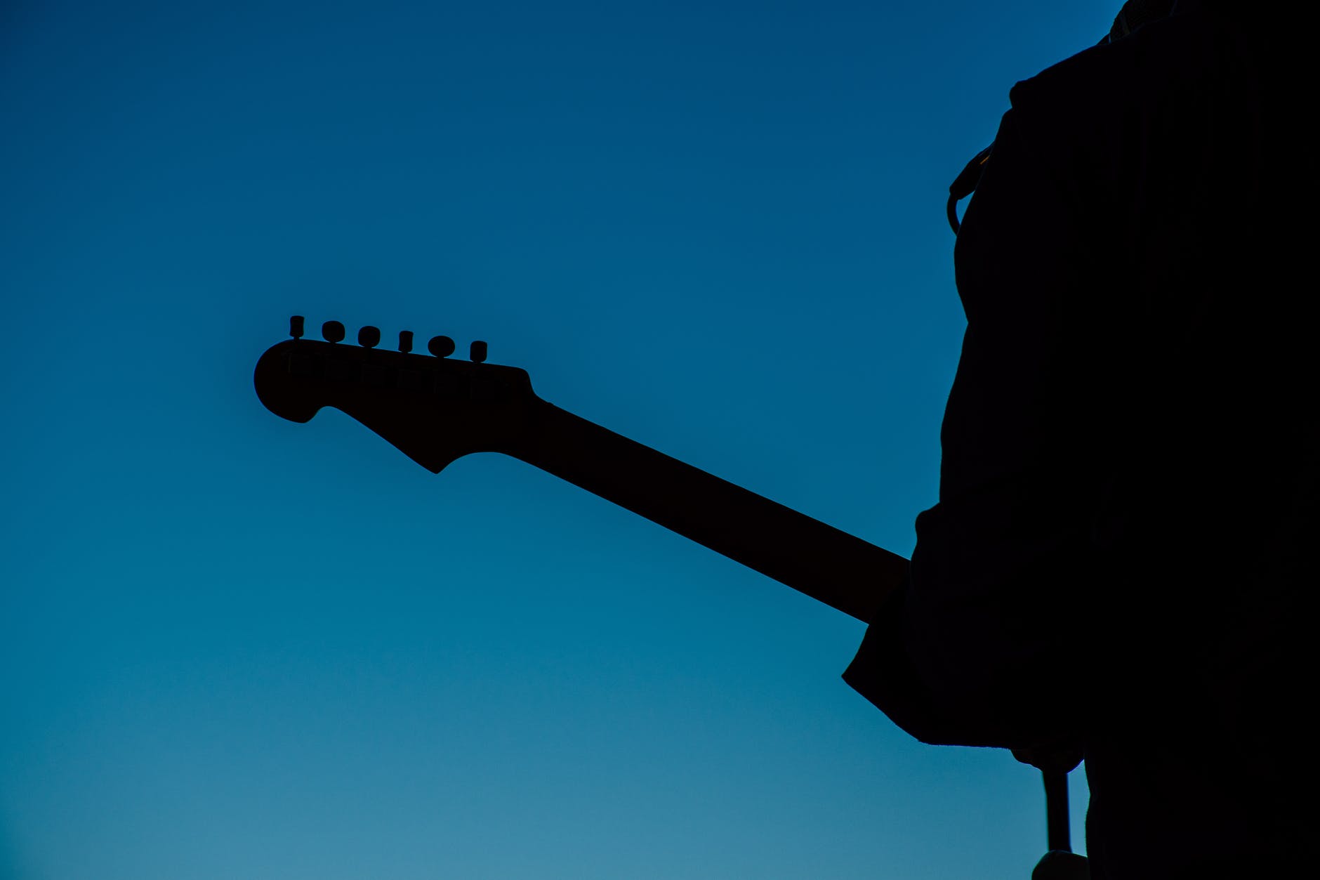silhouette photo of person holding guitar