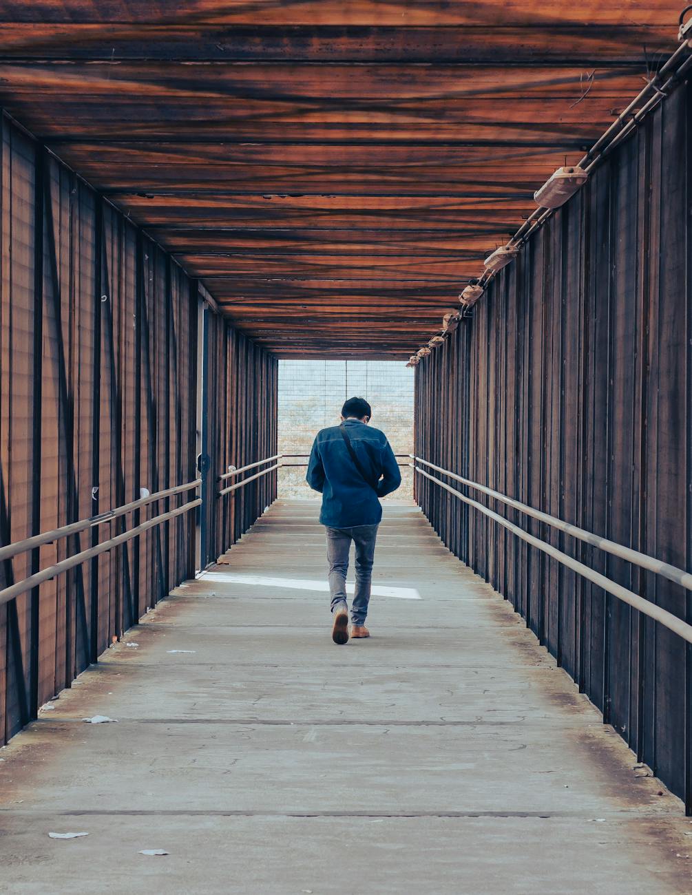 man walking on covered bridge